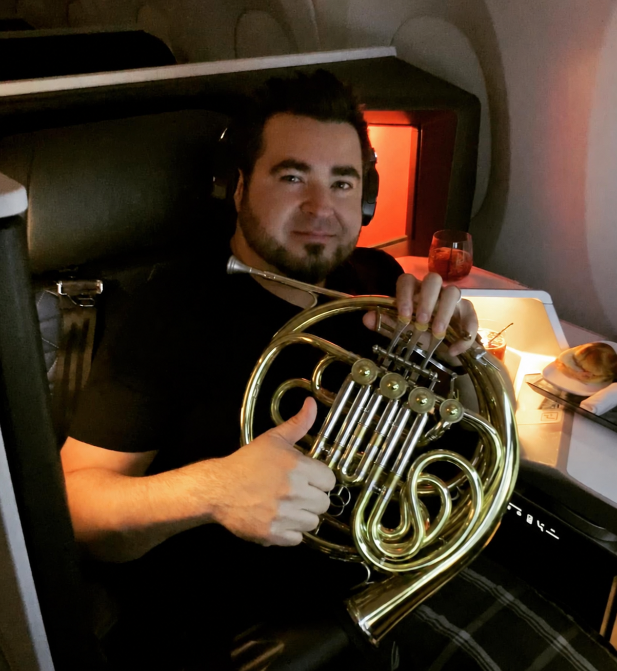 Chris Castellanos traveling aboard an airplane with his French horn