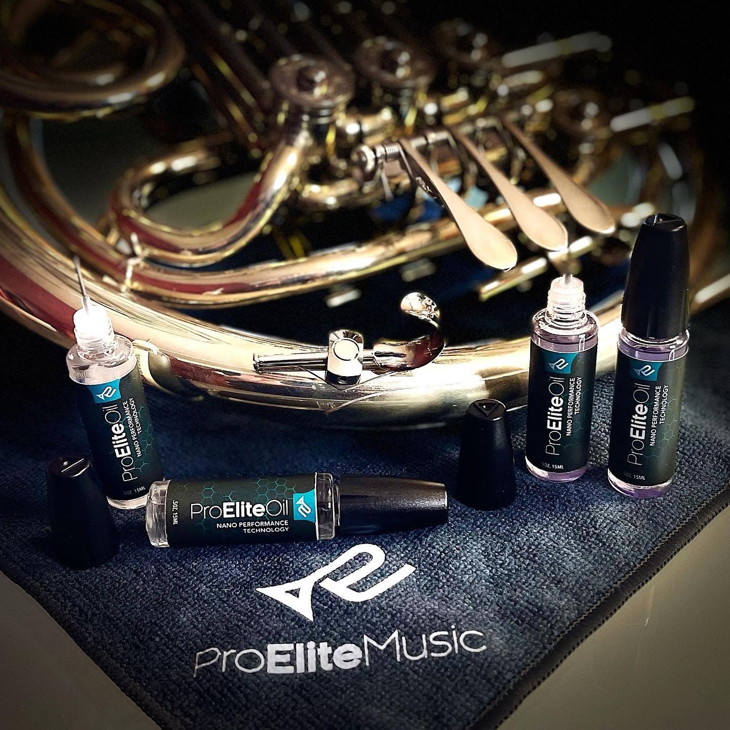 Pro Elite Oil bottles displayed with a French horn